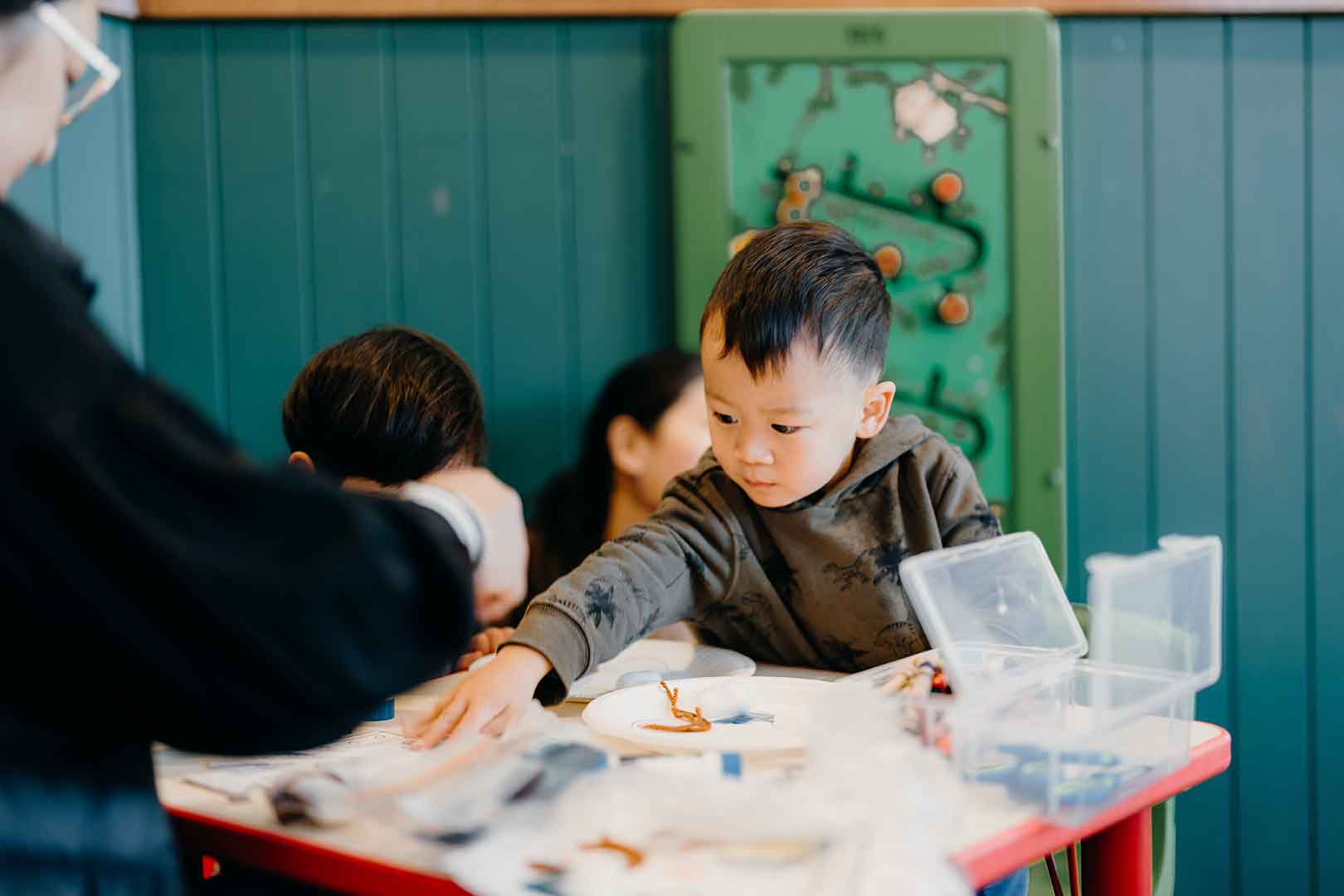 Young child reaching out for colouring materials